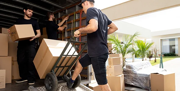 Movers loading boxes onto a dolly to represent benefits of using local moving service in Granger, IN.